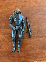 Front view of figure standing next to rifle