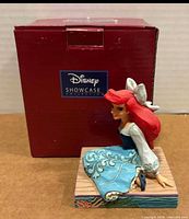 Front view of Ariel figurine beside original red Disney Showcase box