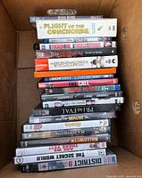 Single photo showing stack of 18 DVD cases in box with visible titles