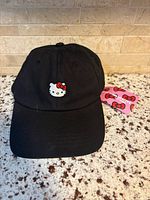 Front view of black Hello Kitty embroidered baseball cap with curved brim