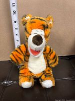 Front view of Tigger plush with measuring tape showing height