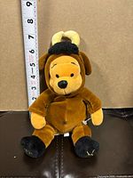 Full view of Winnie the Pooh Taurus plush next to ruler for scale