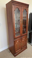 Closed view of glass-door curio cabinet showing exterior finish and hardware
