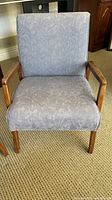 Front view of one armchair showing upholstery pattern and wood frame