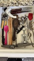 Drawer view with can opener, knives, corkscrew, garlic press, chopsticks and other tools
