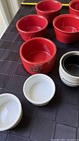 Group of red, white and black/white ramekins and bowls on black table cloth