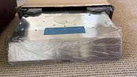 Range hood partially removed from box showing stainless steel front and protective wrap