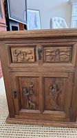 Front view showing carved drawer front, lower door carvings, and keyhole hardware