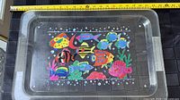 Top view of clear acrylic tray with tropical fish design and tape for scale
