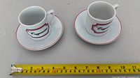 Two cup and saucer sets with tape measure showing scale