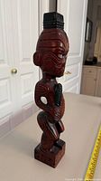 Front left view of full tiki figure showing carved details and inlaid eyes