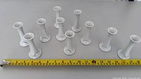 All 10 white porcelain bud vases arranged with tape measure for scale