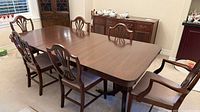 Dining table with six chairs and buffet in background