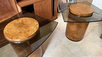 Pair of burl veneer pedestal tables showing round burl caps and smoked glass tops