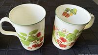 Two mugs showing exterior strawberry design and green rim