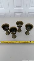 All four goblets standing in a row with tape measure showing scale