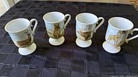 Front view of four hand-painted wildlife mugs
