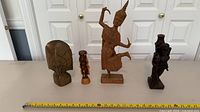 All four wooden figurines with measuring tape for scale