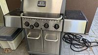 Full view of Broil-Mate stainless steel natural-gas grill showing burners, side shelves, cabinet