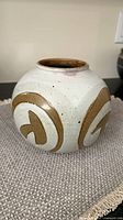 Front view of spherical white and brown stoneware vase
