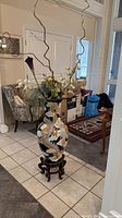 Full view of vase on stand with floral arrangement