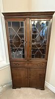 Full view of closed corner china cabinet showing glass doors and lower cabinet