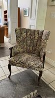 Front view of chair showing floral upholstery, channel back and wood legs
