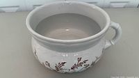 Side view of ceramic chamber pot showing floral transfer and handle