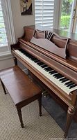 Front view of Willis upright piano with bench showing keyboard and music rack