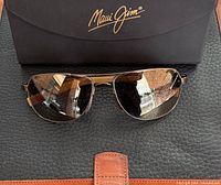 Front view of Maui Jim polarized sunglasses with case behind