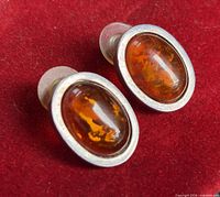 Front view of both earrings showing oval amber-tone cabochons and silver-tone frames