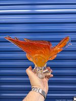 Side view of orange-amber Chalet glass dove bowl held in hand