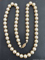 Full view of graduated faux pearl necklace laid out showing overall design and clasp