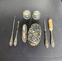 Full layout of eight Birks sterling vanity pieces on dark background