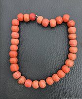 Full view of coral bead necklace on black surface