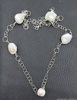 Full view of necklace showing five pearls and chain style