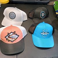Four Reel Life caps laid out showing color variations and front patches