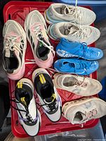 Overview of six pairs of women’s athletic sneakers in red bin