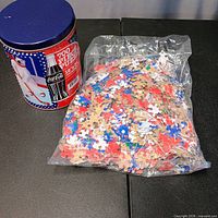 Tin and sealed bag of puzzle pieces overview