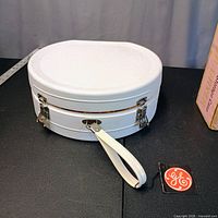 Exterior of white round carry case with handle and GE tag