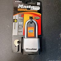 Front view of sealed package showing Master Lock Magnum M176XDLH combination padlock and included key