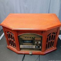 Front view of wood cabinet stereo console showing decorative grilles and control panel