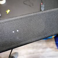 Top surface of black Samsung soundbar, showing texture and nearby remote