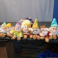 Front view of all eight plush dolls lined on table