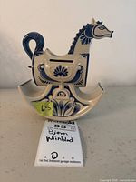 Front view of ceramic horse bank showing blue floral decoration and coin slot