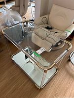 Angled view showing glass top, mirrored bottom shelf, metal frame and casters