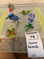 All six Murano glass figurines grouped on glass shelf