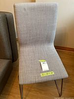 Front view of gray upholstered dining chair showing seat fabric and chrome sled legs