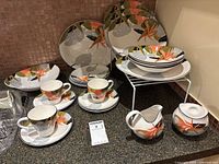 Group view of dinner plates, salad plates, bowls, cups on saucers, creamer and sugar bowl
