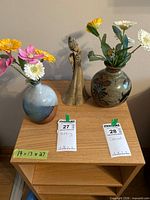 Both vases with flowers and figurine on tabletop